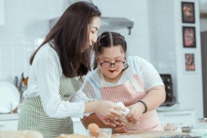 Young Downs Syndrome Couple Baking In Kitchen At Home